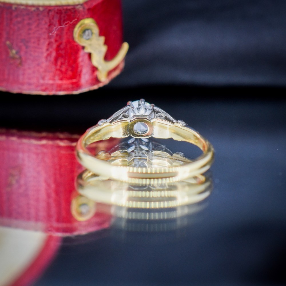 An Art Deco diamond solitaire ring featuring a round cut diamond set between detailed, fan-etched shoulders on an 18ct yellow gold band. View VI
