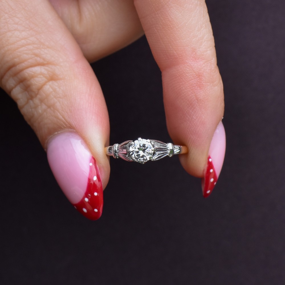 An Art Deco diamond solitaire ring featuring a round cut diamond set between detailed, fan-etched shoulders on an 18ct yellow gold band. View IX