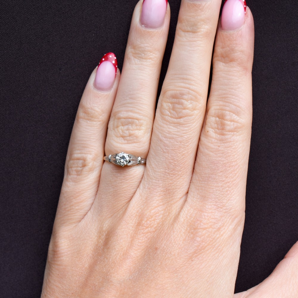An Art Deco diamond solitaire ring featuring a round cut diamond set between detailed, fan-etched shoulders on an 18ct yellow gold band. View XII