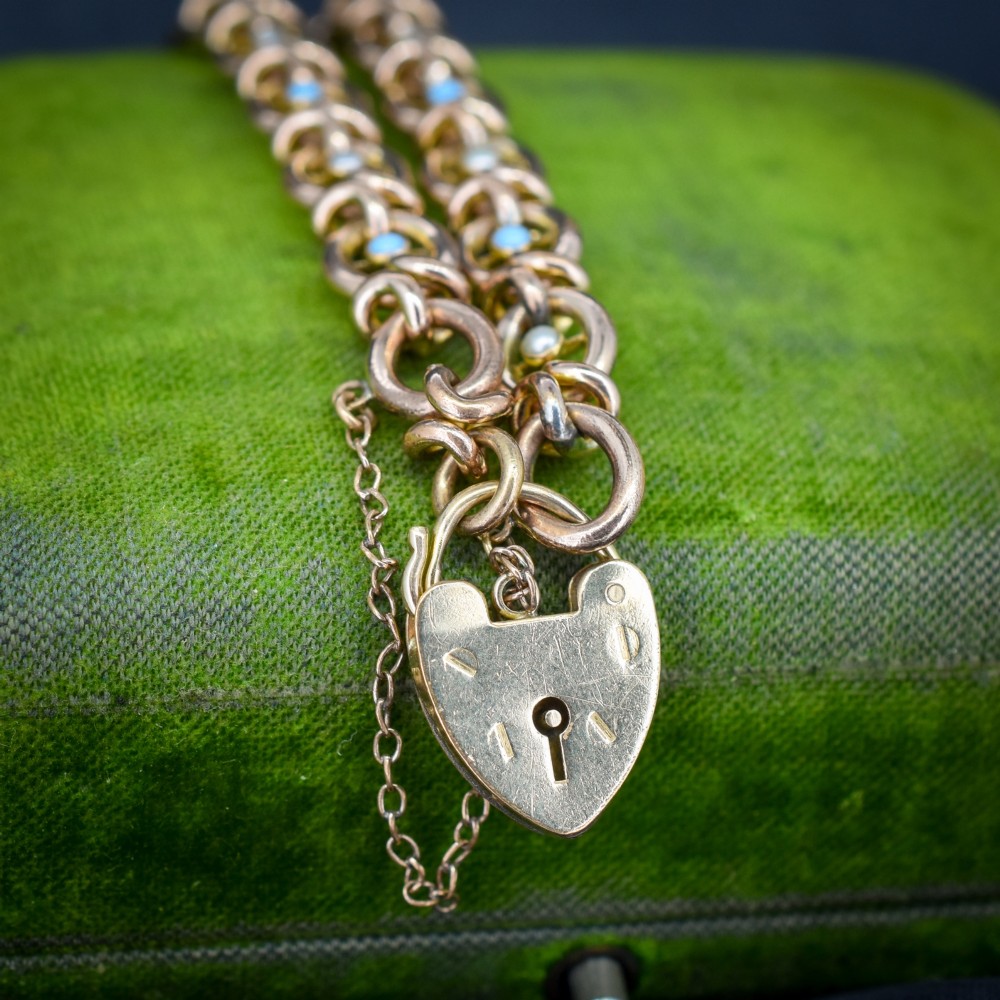 An antique rolled gold chain bracelet inset with alternating seed pearls and turquoise cabochons, featuring a heart-shaped padlock clasp with safety chain. View II