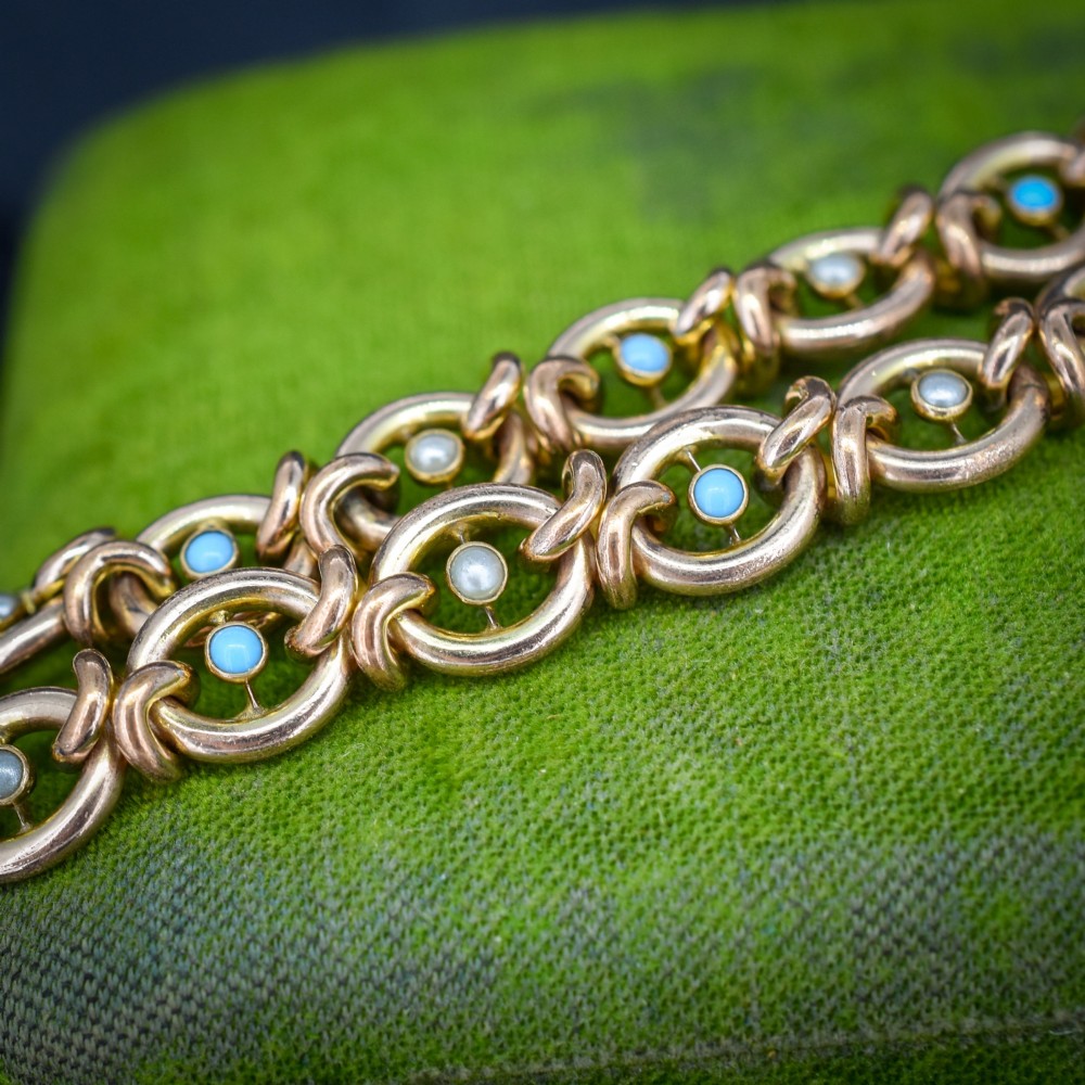 An antique rolled gold chain bracelet inset with alternating seed pearls and turquoise cabochons, featuring a heart-shaped padlock clasp with safety chain. View III