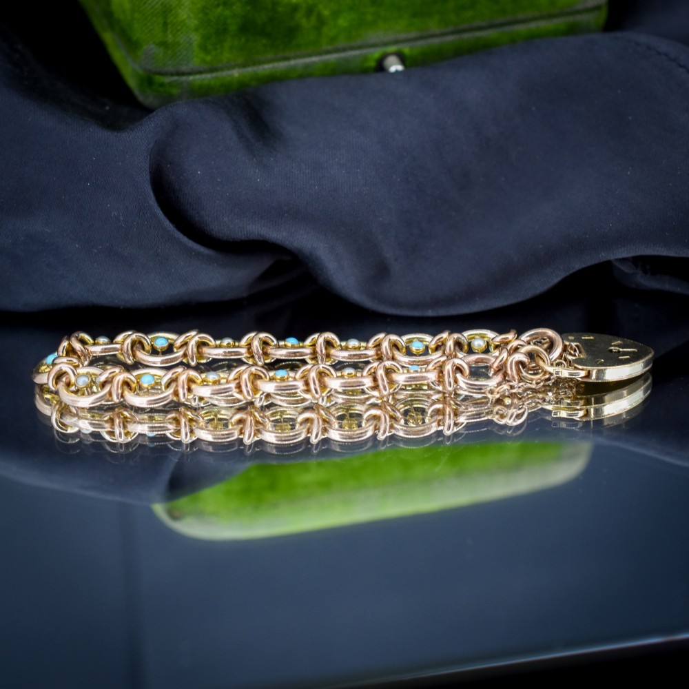 An antique rolled gold chain bracelet inset with alternating seed pearls and turquoise cabochons, featuring a heart-shaped padlock clasp with safety chain. View V