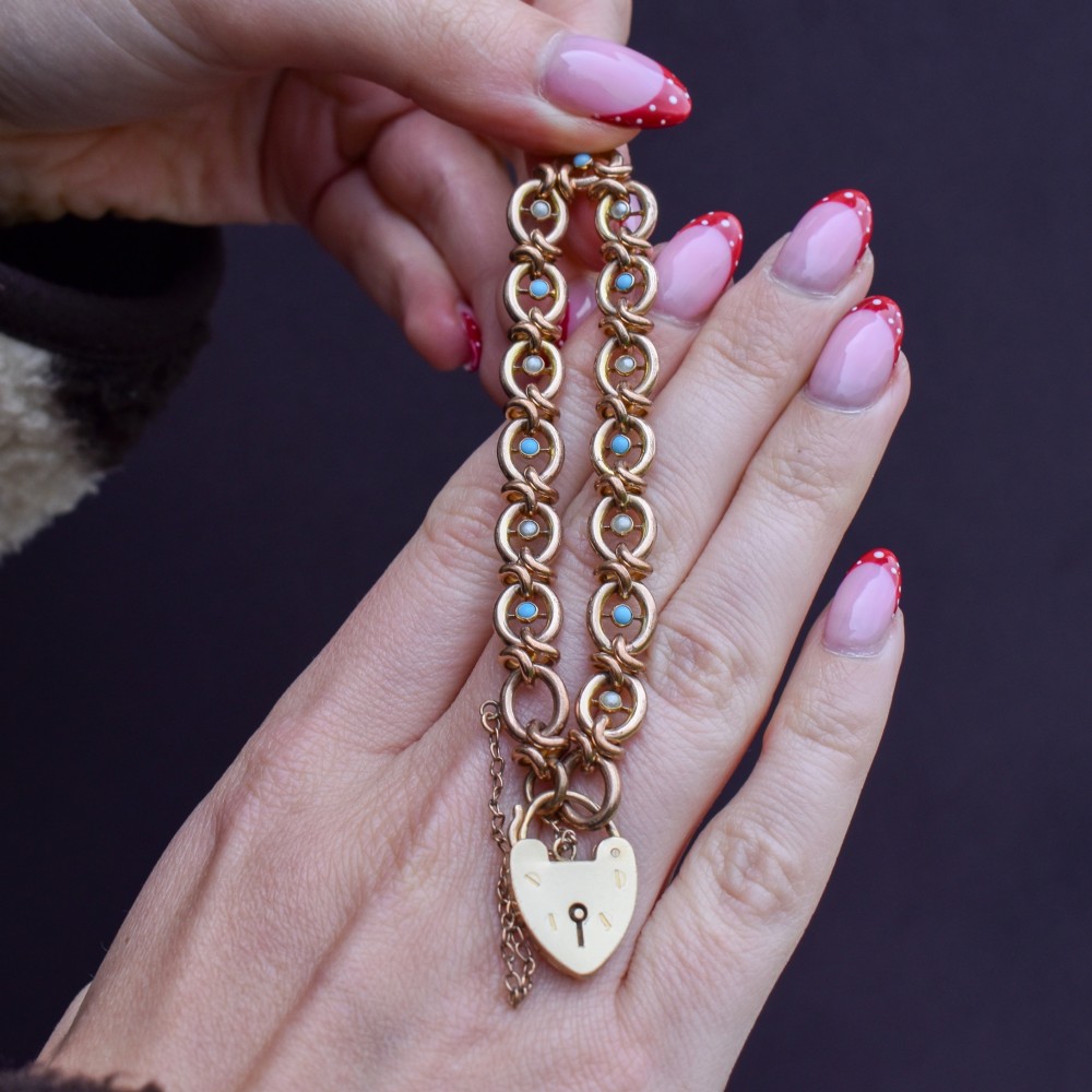 An antique rolled gold chain bracelet inset with alternating seed pearls and turquoise cabochons, featuring a heart-shaped padlock clasp with safety chain. View VII