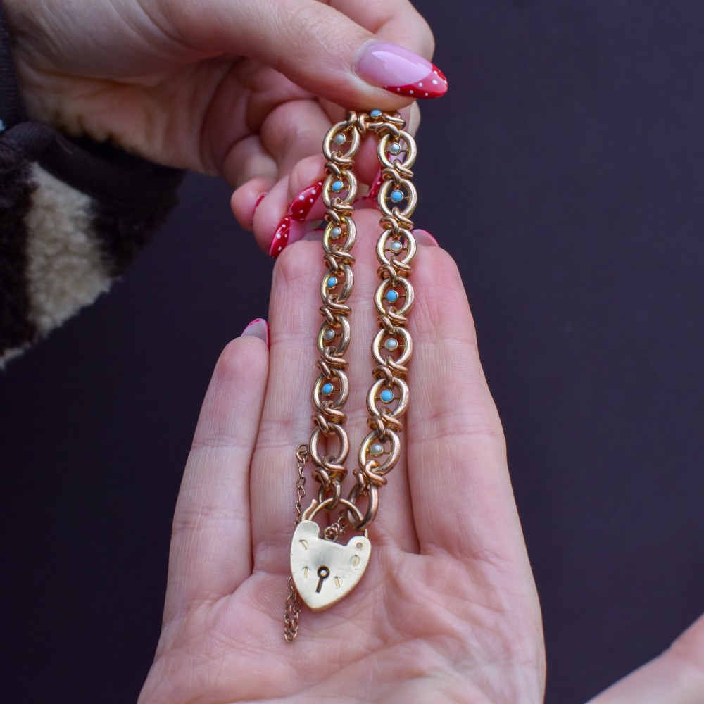 An antique rolled gold chain bracelet inset with alternating seed pearls and turquoise cabochons, featuring a heart-shaped padlock clasp with safety chain. View VIII