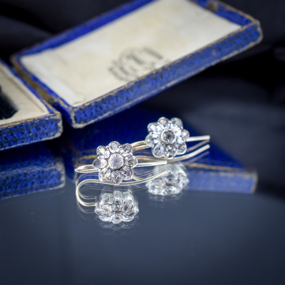 A pair of antique Georgian flower-shaped cluster earrings featuring clear paste stones set in silver with gold ear wires. View V