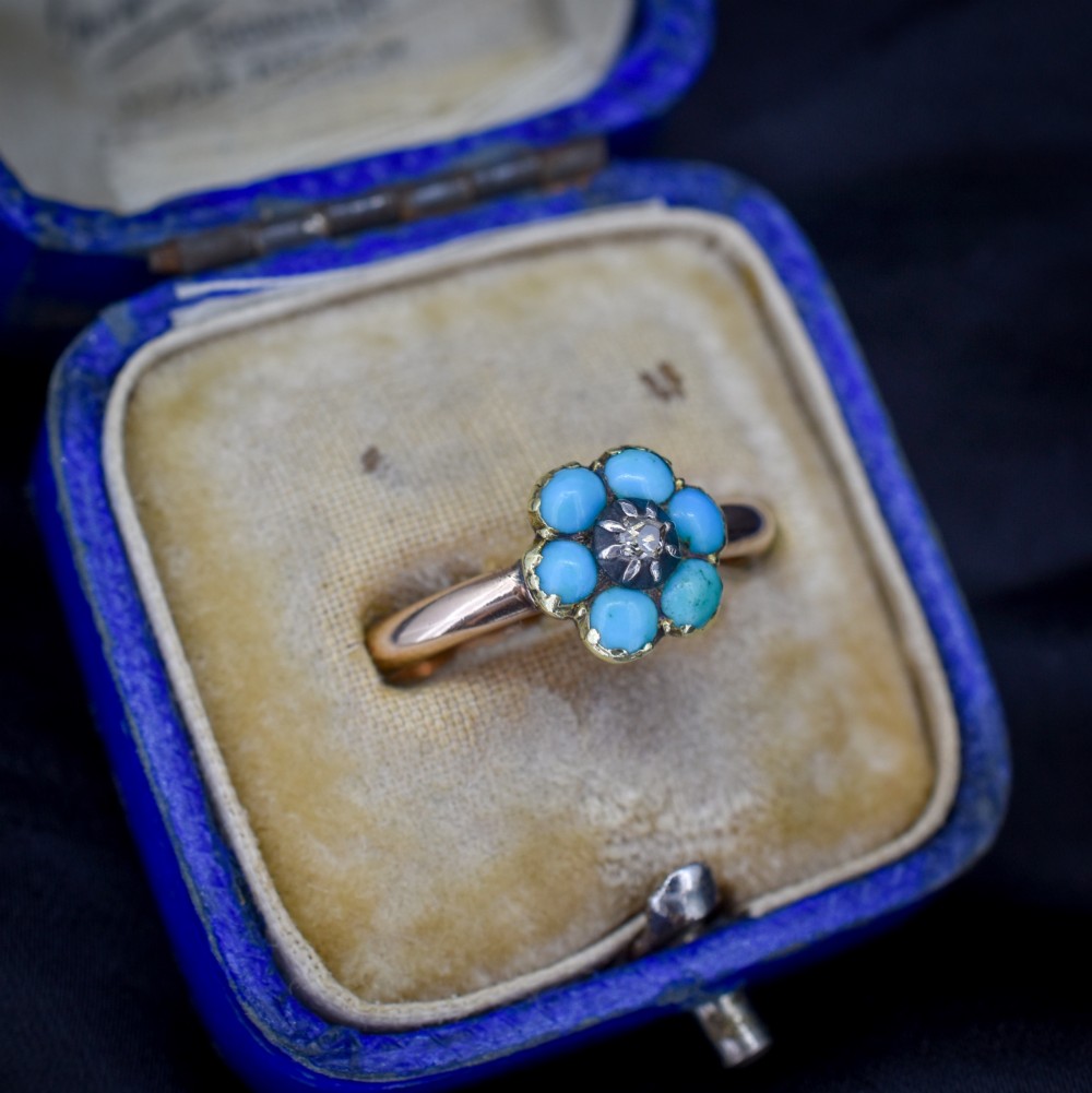 An antique 15ct yellow gold ring featuring a central diamond surrounded by six turquoise cabochons forming a floral cluster. View II