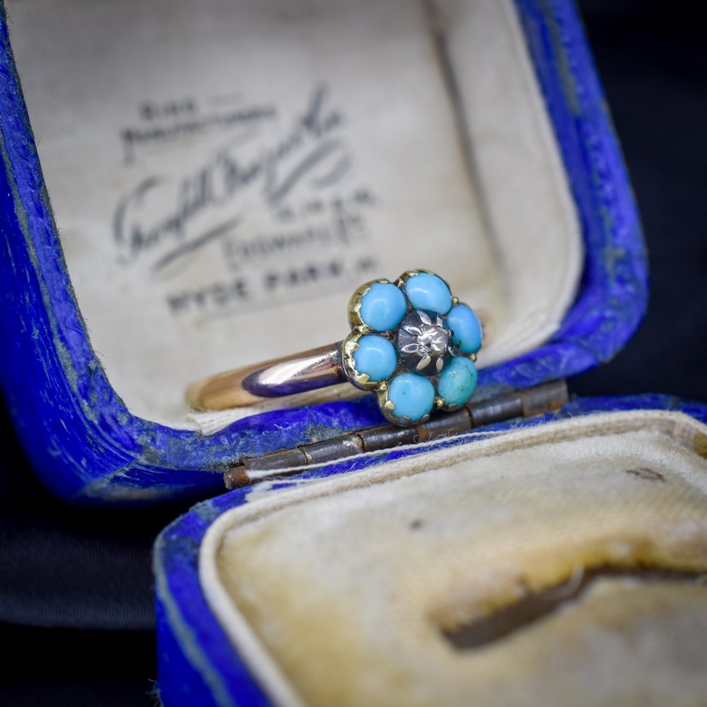 An antique 15ct yellow gold ring featuring a central diamond surrounded by six turquoise cabochons forming a floral cluster. View IV
