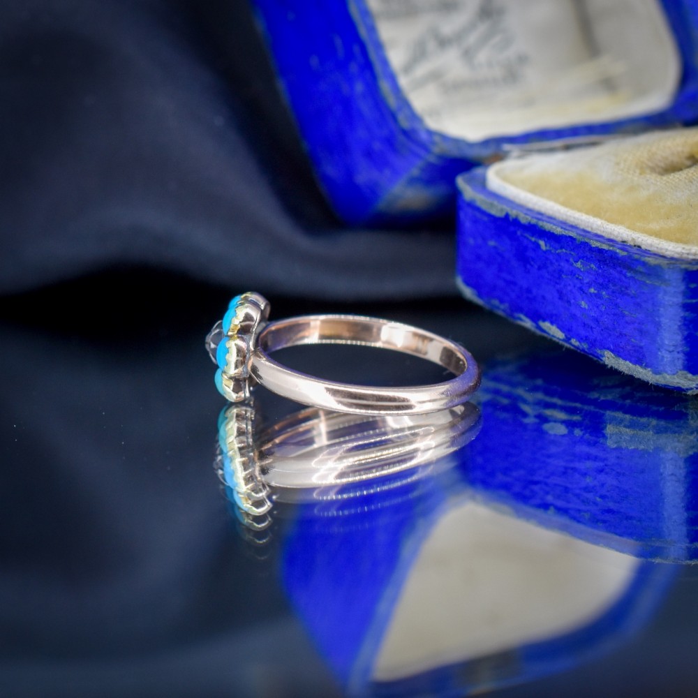 An antique 15ct yellow gold ring featuring a central diamond surrounded by six turquoise cabochons forming a floral cluster. View V