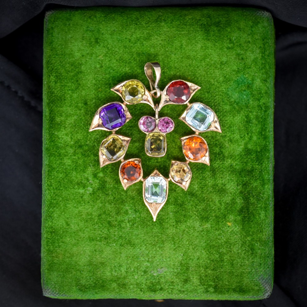 An antique 9ct yellow gold floral drop pendant composed of leaf-shaped settings encasing various multi-coloured faceted gemstones.