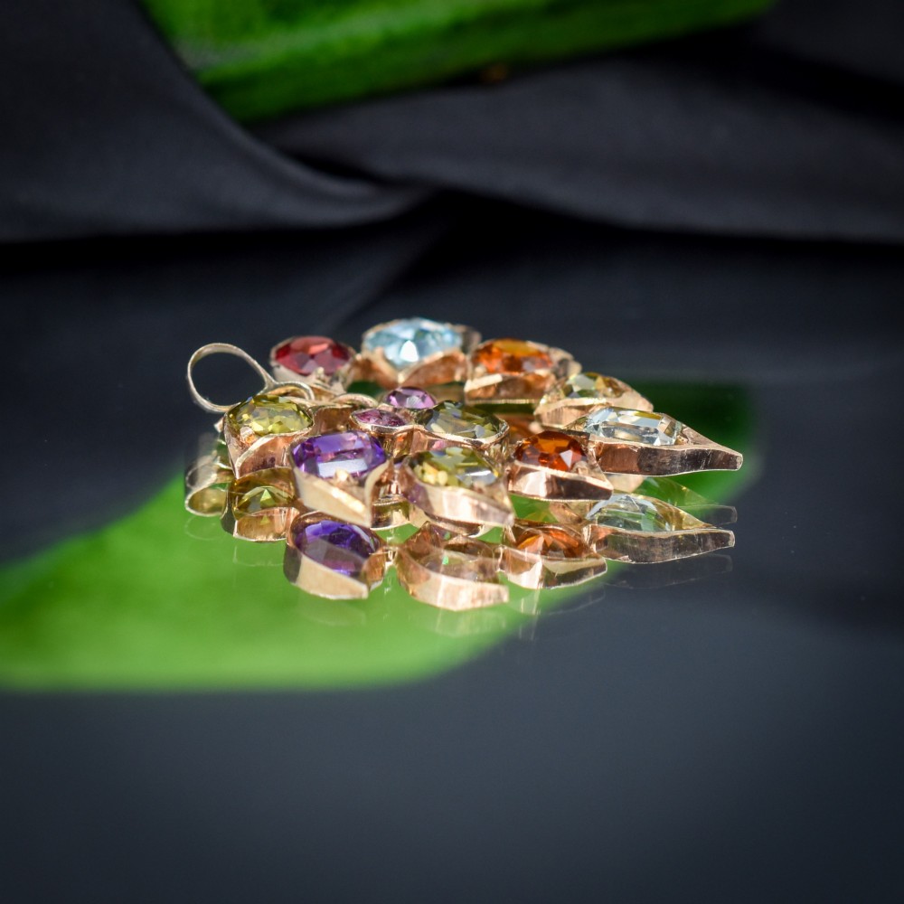 An antique 9ct yellow gold floral drop pendant composed of leaf-shaped settings encasing various multi-coloured faceted gemstones. View II