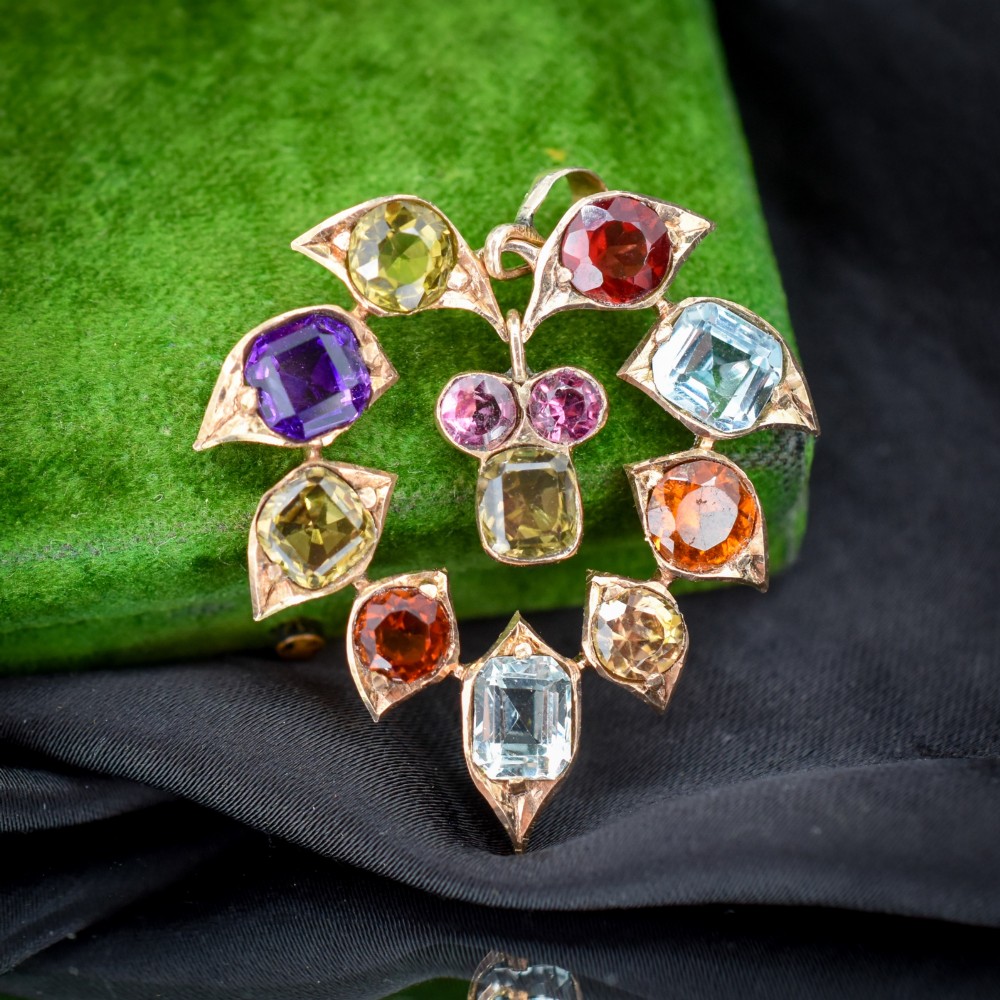 An antique 9ct yellow gold floral drop pendant composed of leaf-shaped settings encasing various multi-coloured faceted gemstones. View V