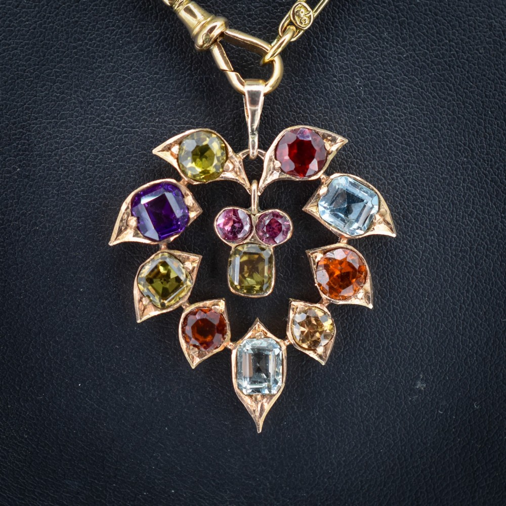 An antique 9ct yellow gold floral drop pendant composed of leaf-shaped settings encasing various multi-coloured faceted gemstones. View VI