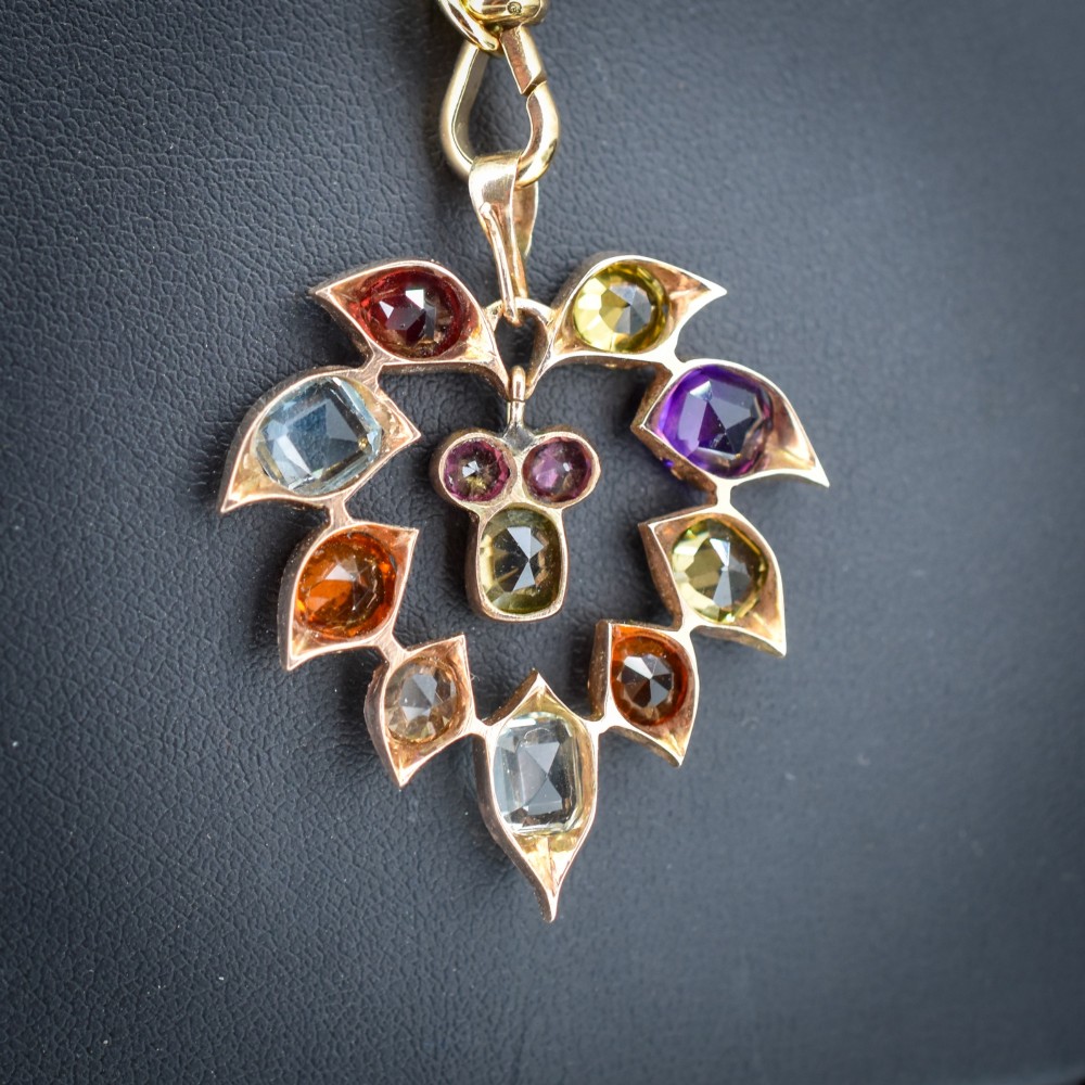 An antique 9ct yellow gold floral drop pendant composed of leaf-shaped settings encasing various multi-coloured faceted gemstones. View VII
