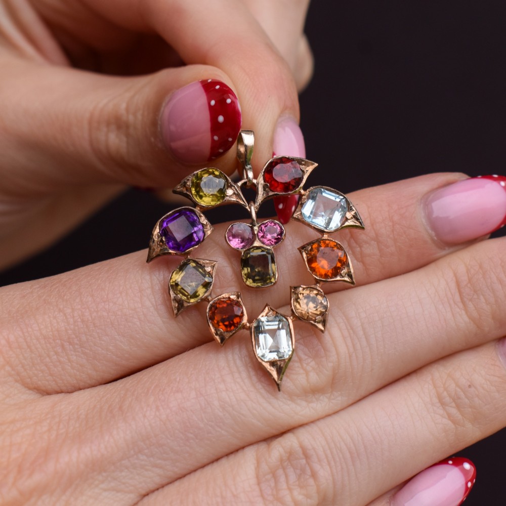 An antique 9ct yellow gold floral drop pendant composed of leaf-shaped settings encasing various multi-coloured faceted gemstones. View IX
