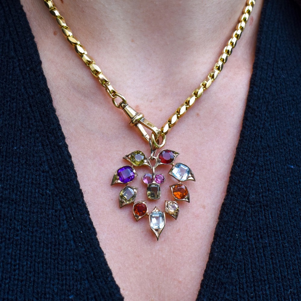 An antique 9ct yellow gold floral drop pendant composed of leaf-shaped settings encasing various multi-coloured faceted gemstones. View XI