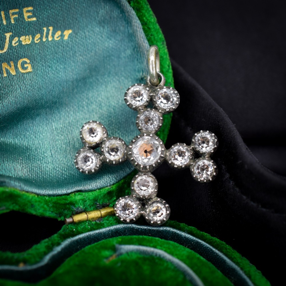 A Georgian silver bottony cross pendant set with clear faceted paste stones featuring black dot culets.