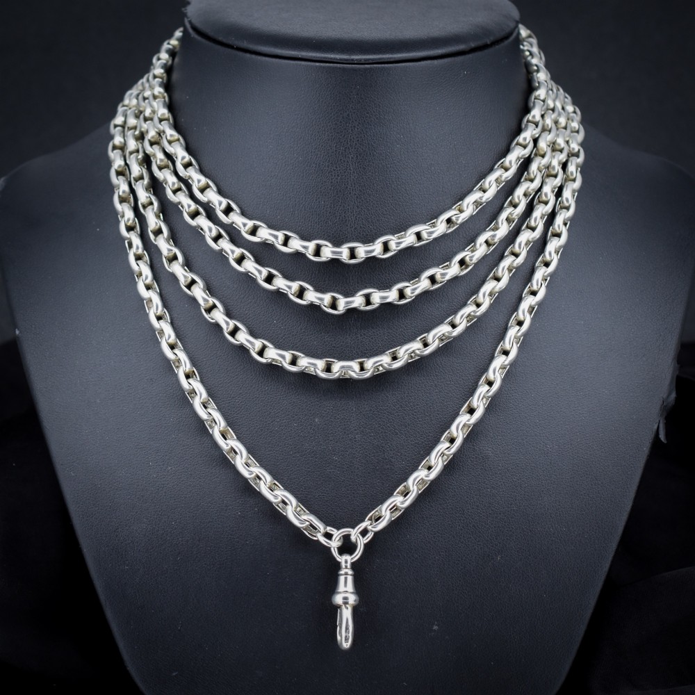 An antique sterling silver long guard chain featuring belcher links and a dog clip clasp, wrapped in multiple layers on a display bust.