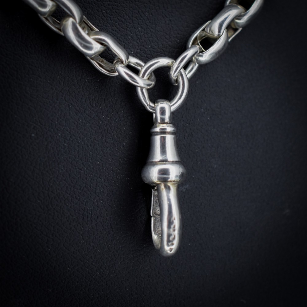 An antique sterling silver long guard chain featuring belcher links and a dog clip clasp, wrapped in multiple layers on a display bust. View IV