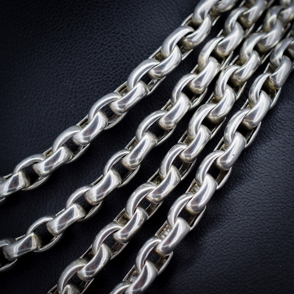 An antique sterling silver long guard chain featuring belcher links and a dog clip clasp, wrapped in multiple layers on a display bust. View V