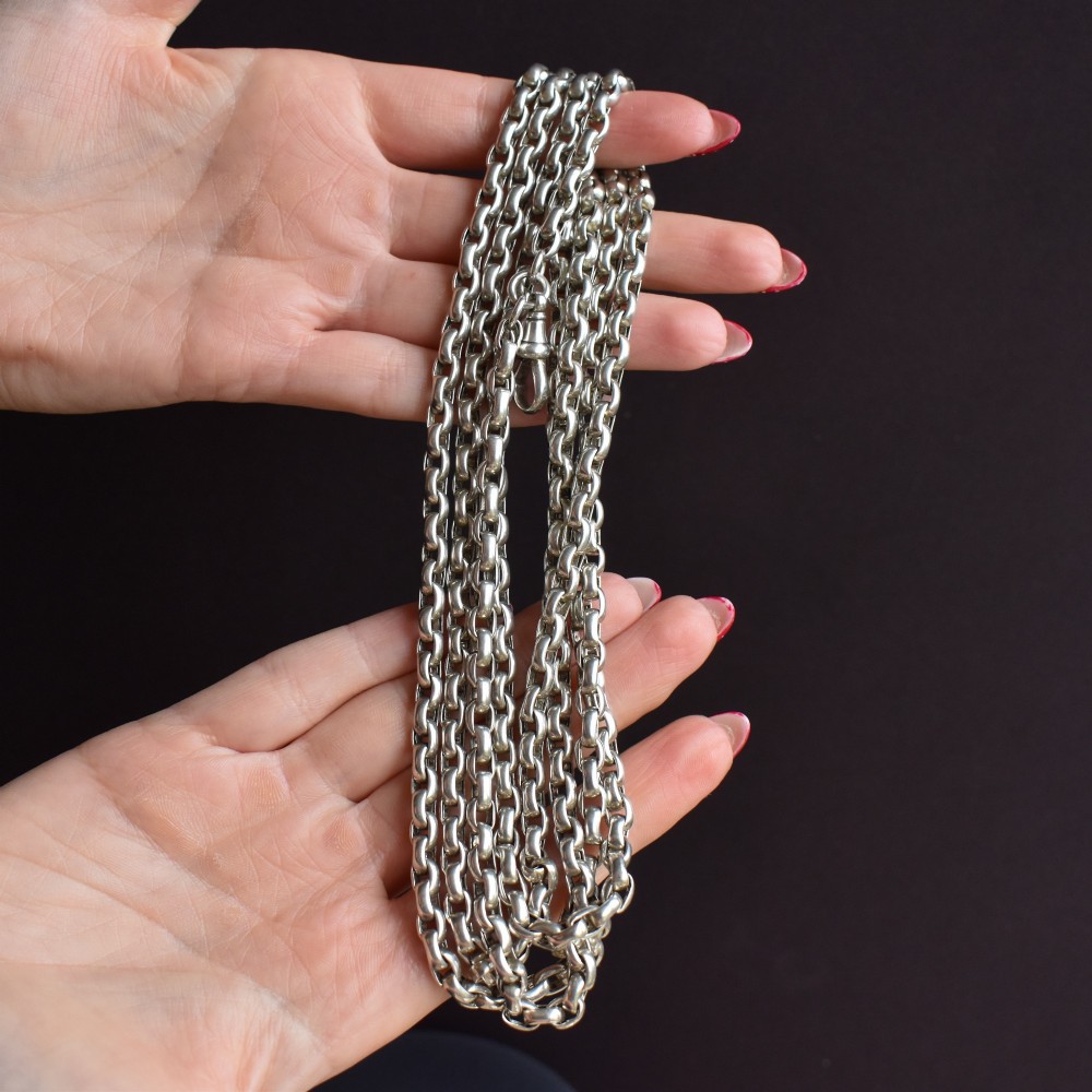 An antique sterling silver long guard chain featuring belcher links and a dog clip clasp, wrapped in multiple layers on a display bust. View IX