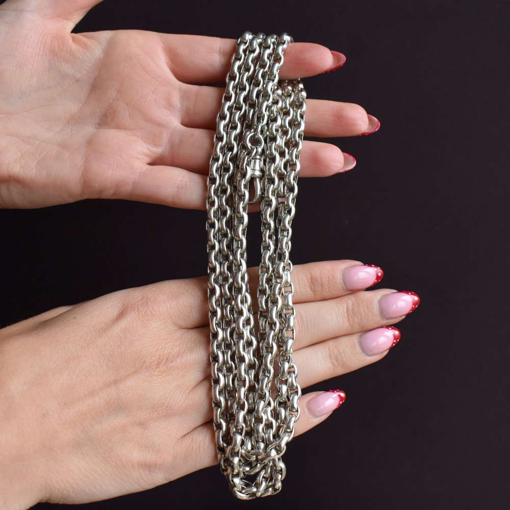 An antique sterling silver long guard chain featuring belcher links and a dog clip clasp, wrapped in multiple layers on a display bust. View X