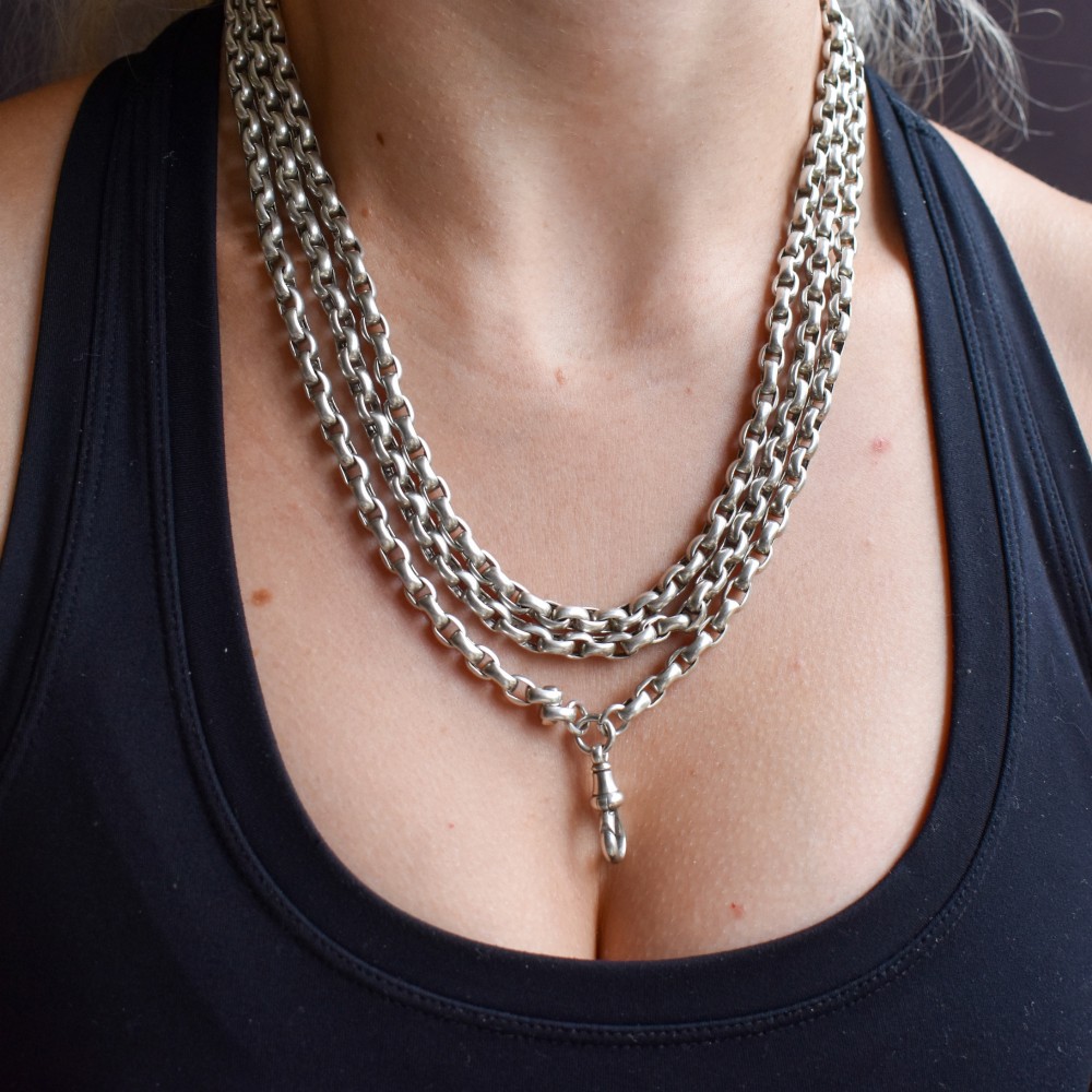 An antique sterling silver long guard chain featuring belcher links and a dog clip clasp, wrapped in multiple layers on a display bust. View XI