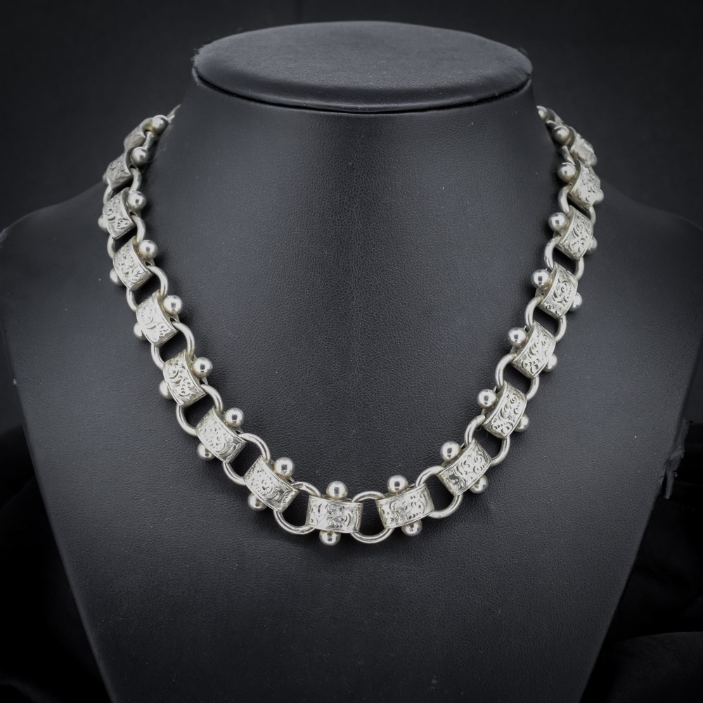 An antique Victorian sterling silver collar necklace featuring wide engraved rectangular links accented with silver beads and linked by circular rings.
