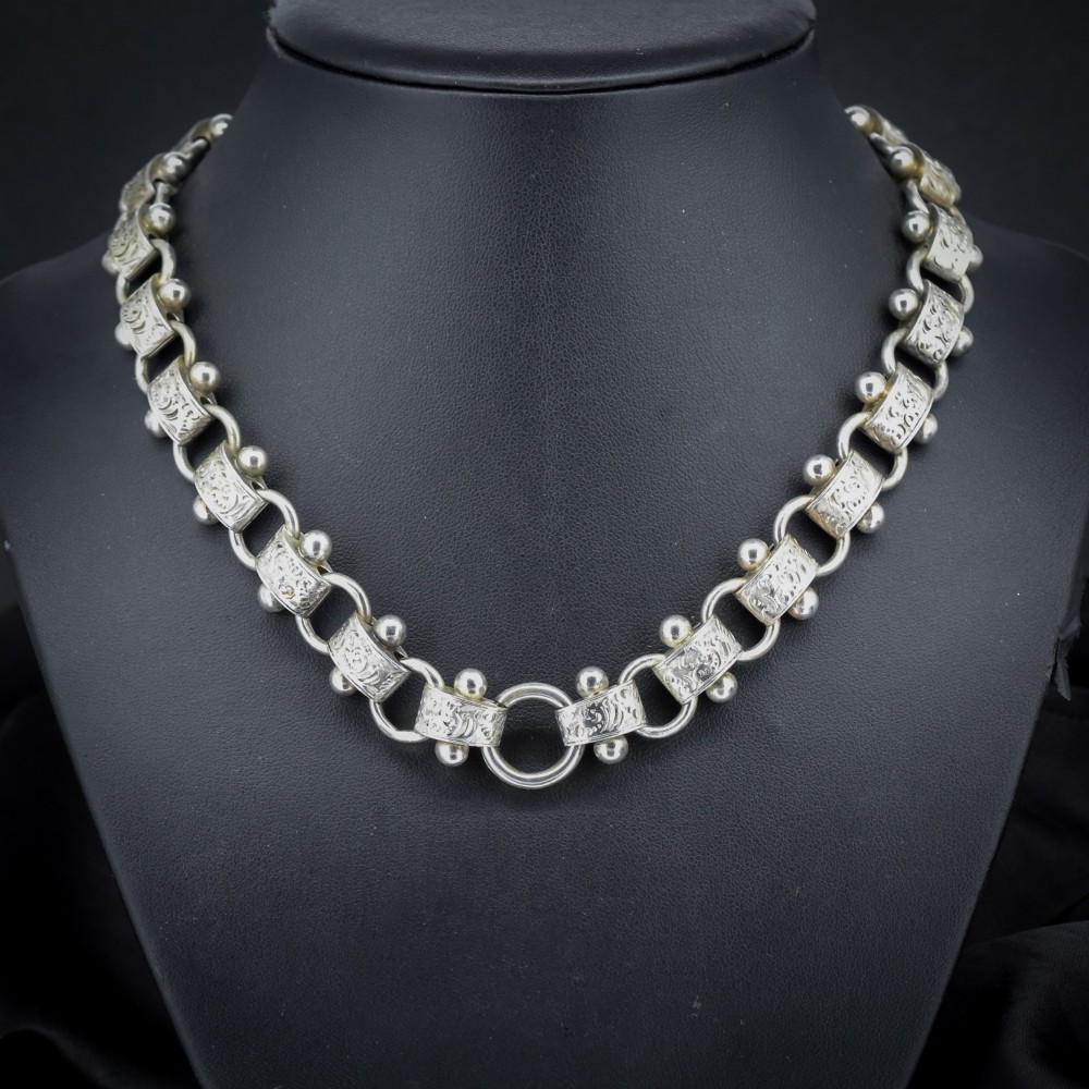 An antique Victorian sterling silver collar necklace featuring wide engraved rectangular links accented with silver beads and linked by circular rings. View II