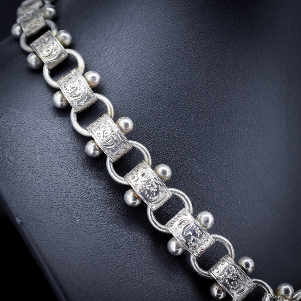 An antique Victorian sterling silver collar necklace featuring wide engraved rectangular links accented with silver beads and linked by circular rings. View III