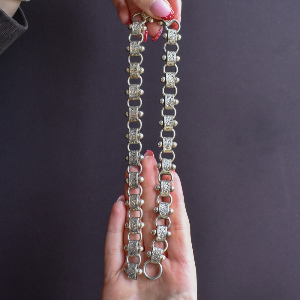 An antique Victorian sterling silver collar necklace featuring wide engraved rectangular links accented with silver beads and linked by circular rings. View VI
