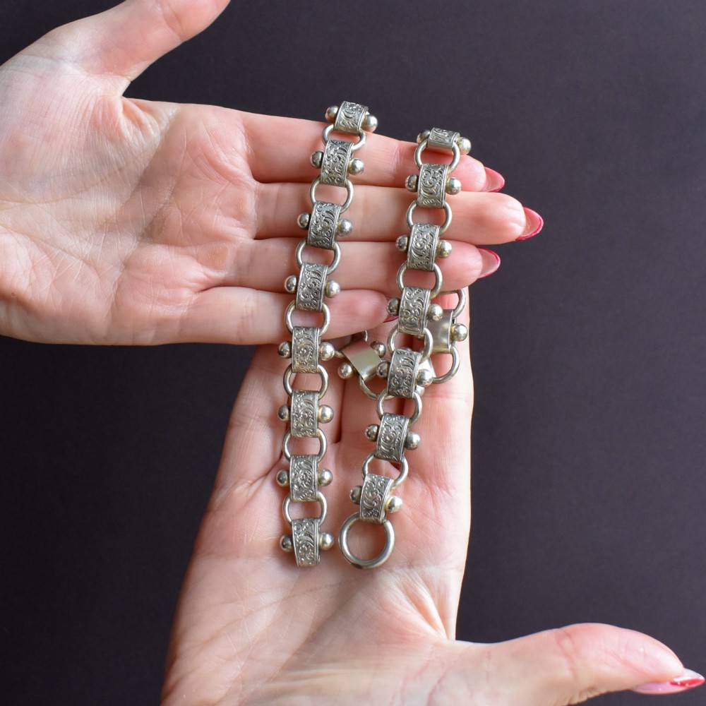 An antique Victorian sterling silver collar necklace featuring wide engraved rectangular links accented with silver beads and linked by circular rings. View VII