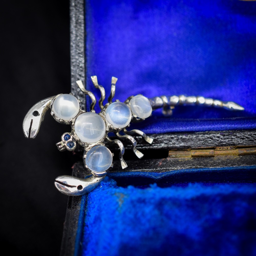 An antique silver scorpion brooch set with five circular cabochon moonstones along its body. View II