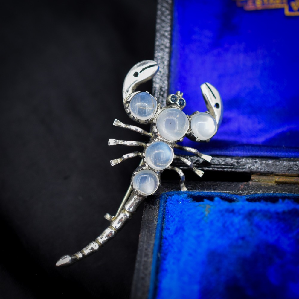 An antique silver scorpion brooch set with five circular cabochon moonstones along its body. View III
