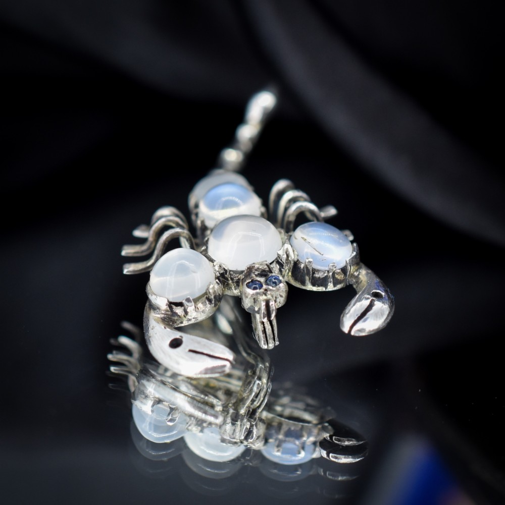 An antique silver scorpion brooch set with five circular cabochon moonstones along its body. View V