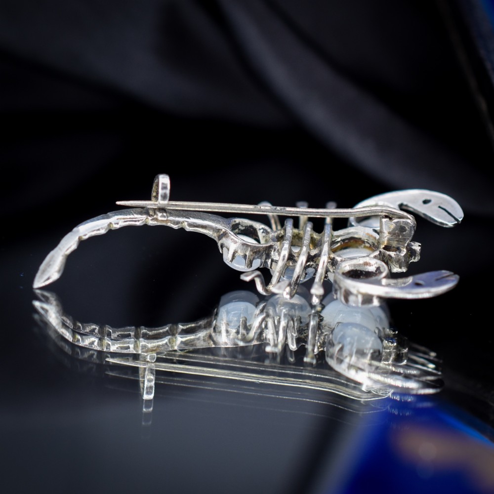 An antique silver scorpion brooch set with five circular cabochon moonstones along its body. View VII