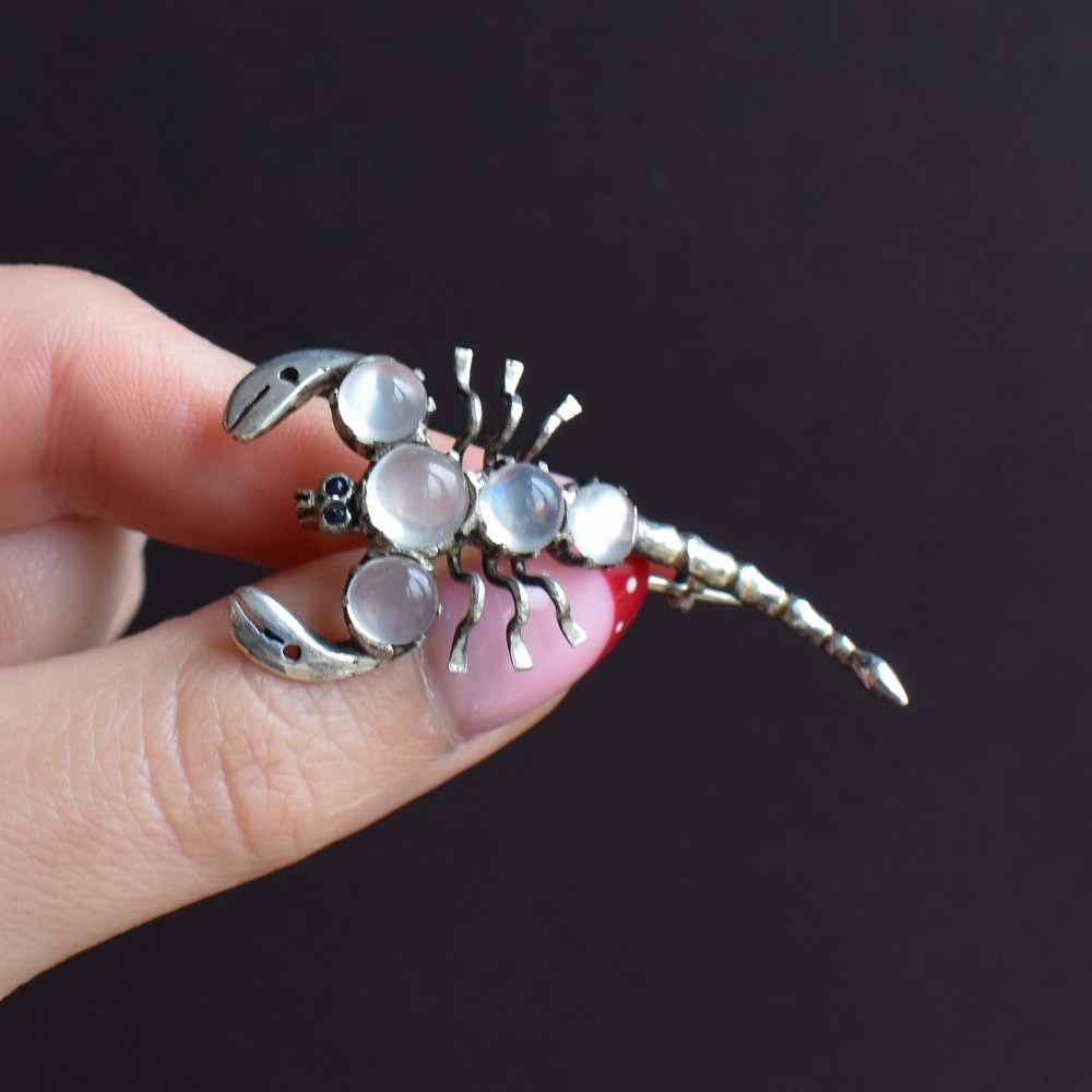 An antique silver scorpion brooch set with five circular cabochon moonstones along its body. View VIII