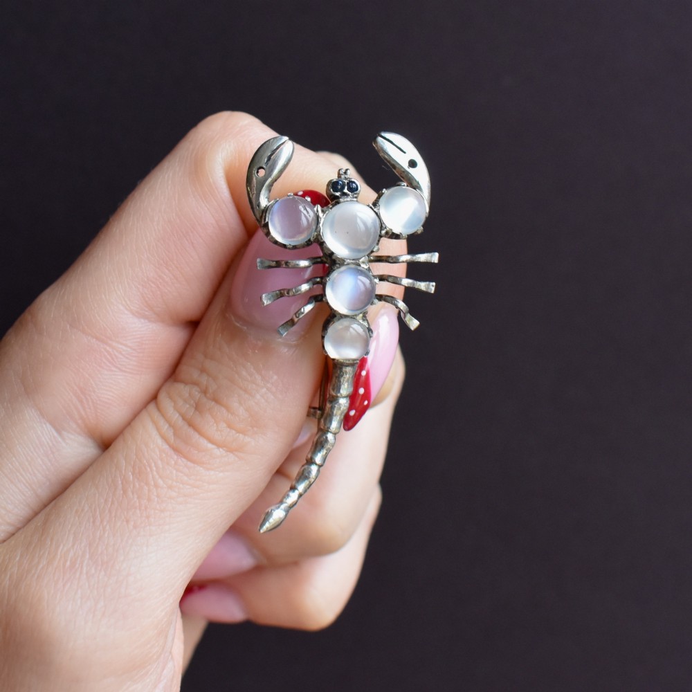 An antique silver scorpion brooch set with five circular cabochon moonstones along its body. View IX