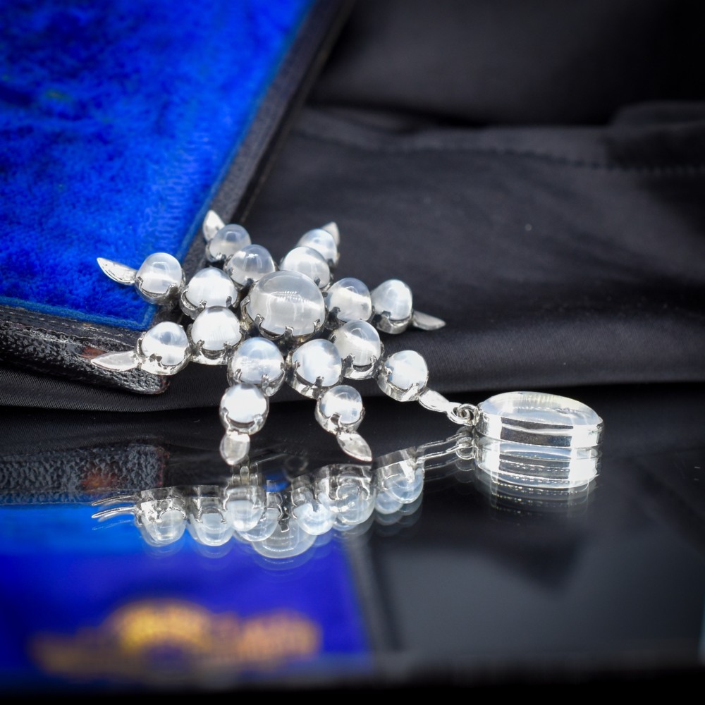 A Victorian silver starburst brooch set with round cabochon moonstones and a suspended oval moonstone drop. View IV