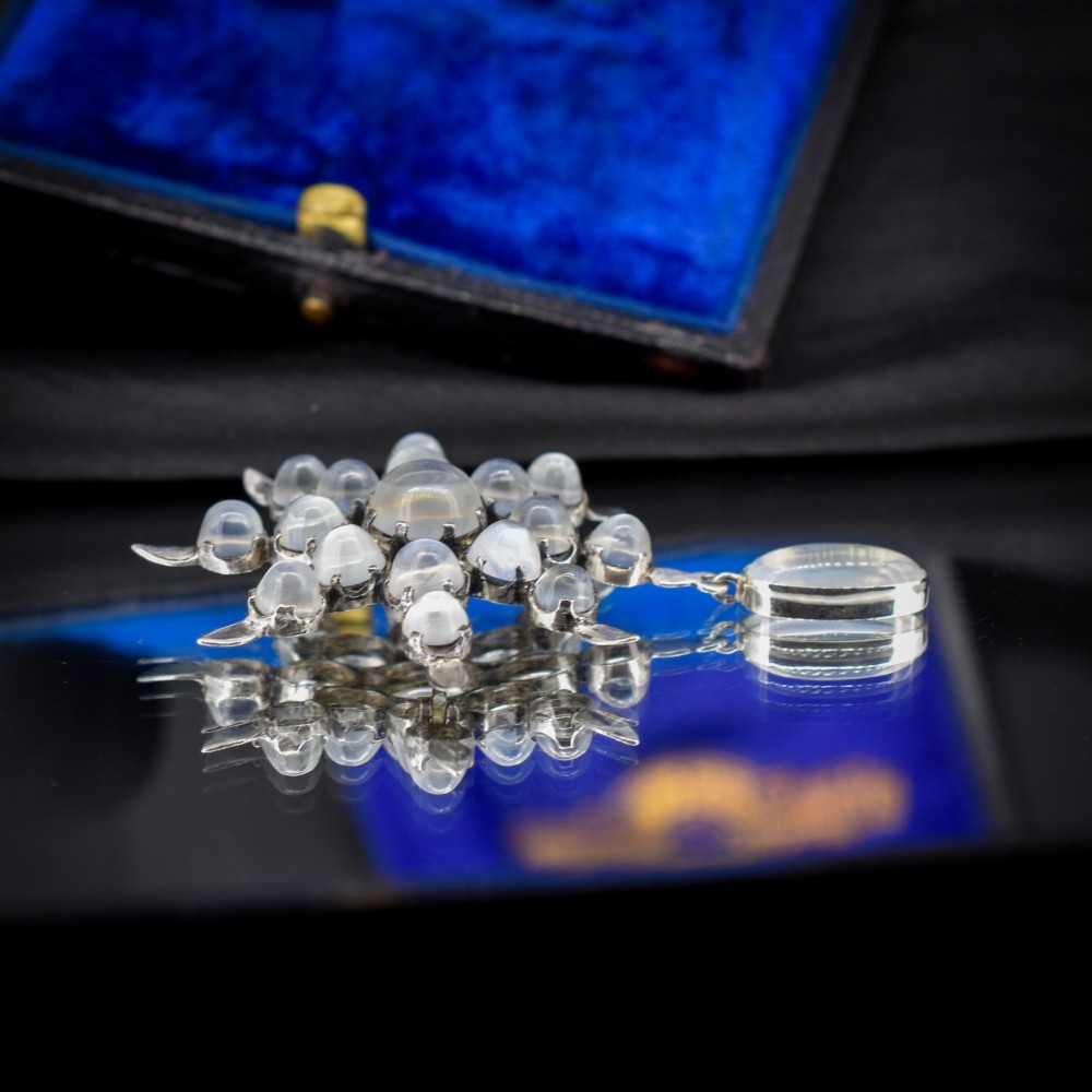 A Victorian silver starburst brooch set with round cabochon moonstones and a suspended oval moonstone drop. View V