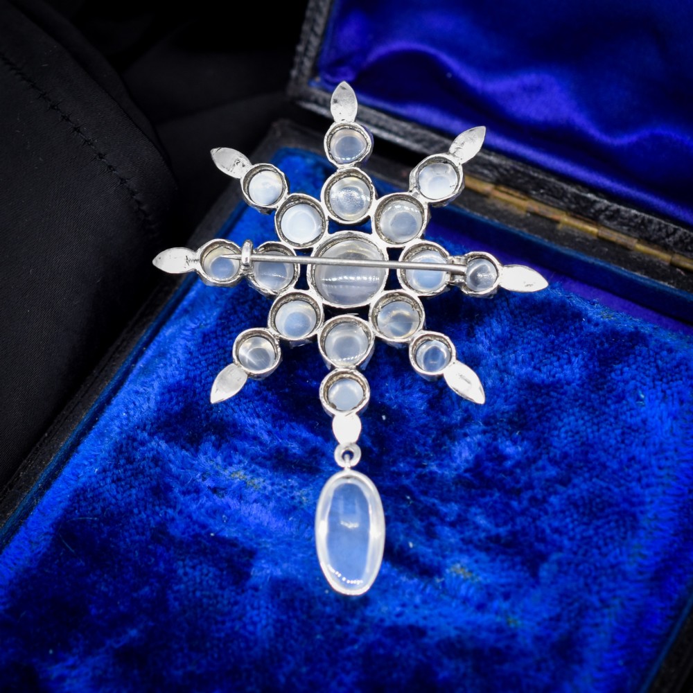 A Victorian silver starburst brooch set with round cabochon moonstones and a suspended oval moonstone drop. View VI