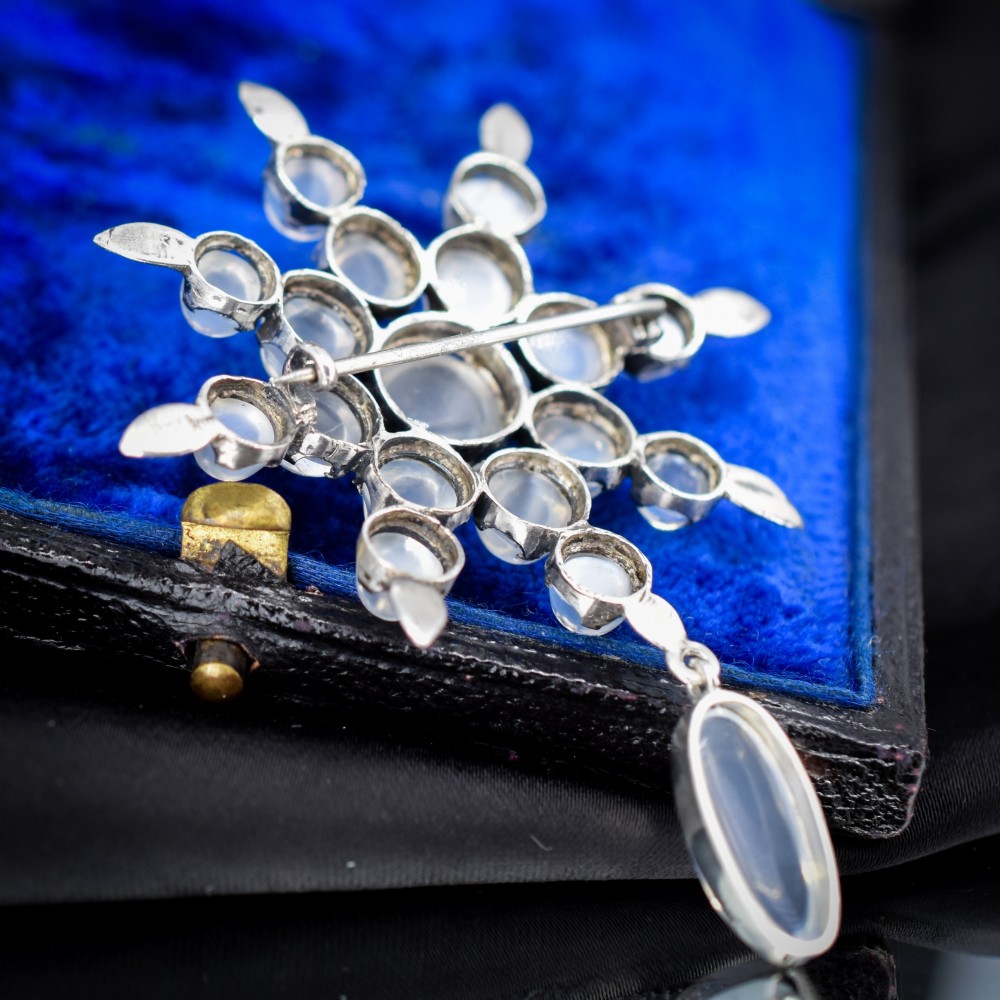 A Victorian silver starburst brooch set with round cabochon moonstones and a suspended oval moonstone drop. View VII