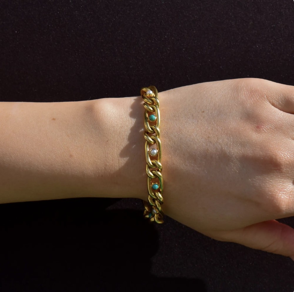 An antique 15ct yellow gold curb link bracelet inset with alternating pearls and cabochon turquoise stones, featuring a fitted safety chain. View X