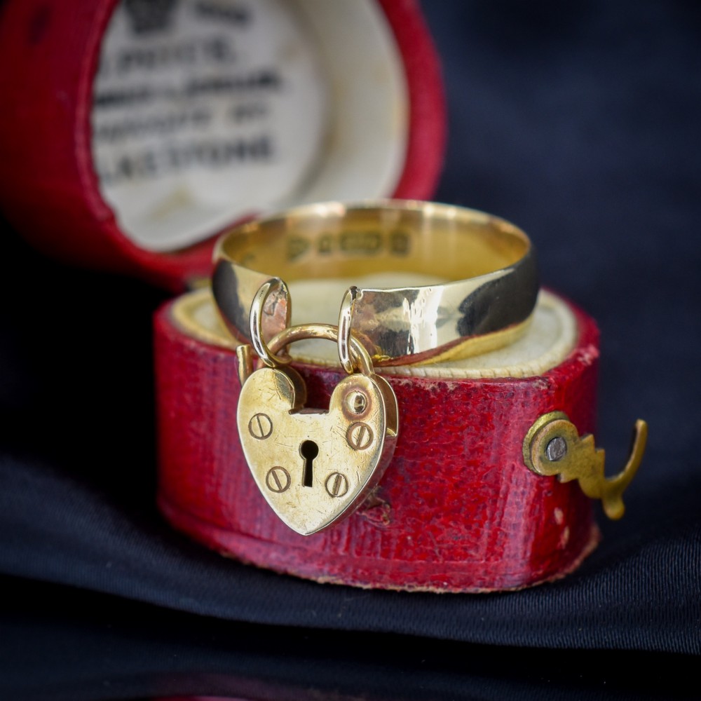 A late Victorian 9ct yellow gold band ring featuring a suspended heart-shaped padlock charm with keyhole detail. View II
