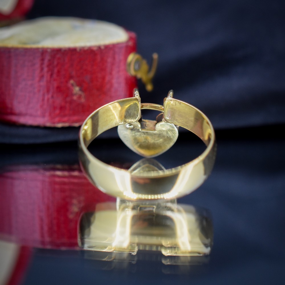 A late Victorian 9ct yellow gold band ring featuring a suspended heart-shaped padlock charm with keyhole detail. View V