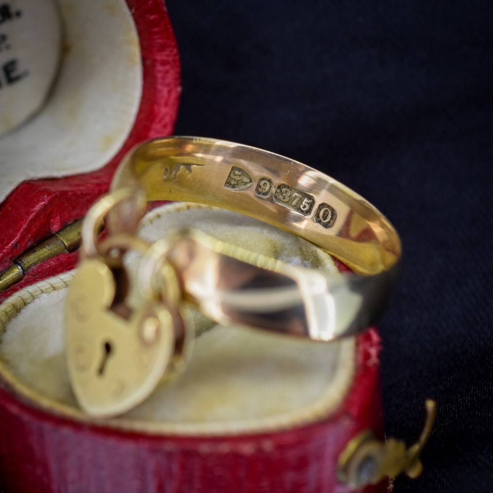 A late Victorian 9ct yellow gold band ring featuring a suspended heart-shaped padlock charm with keyhole detail. View VII