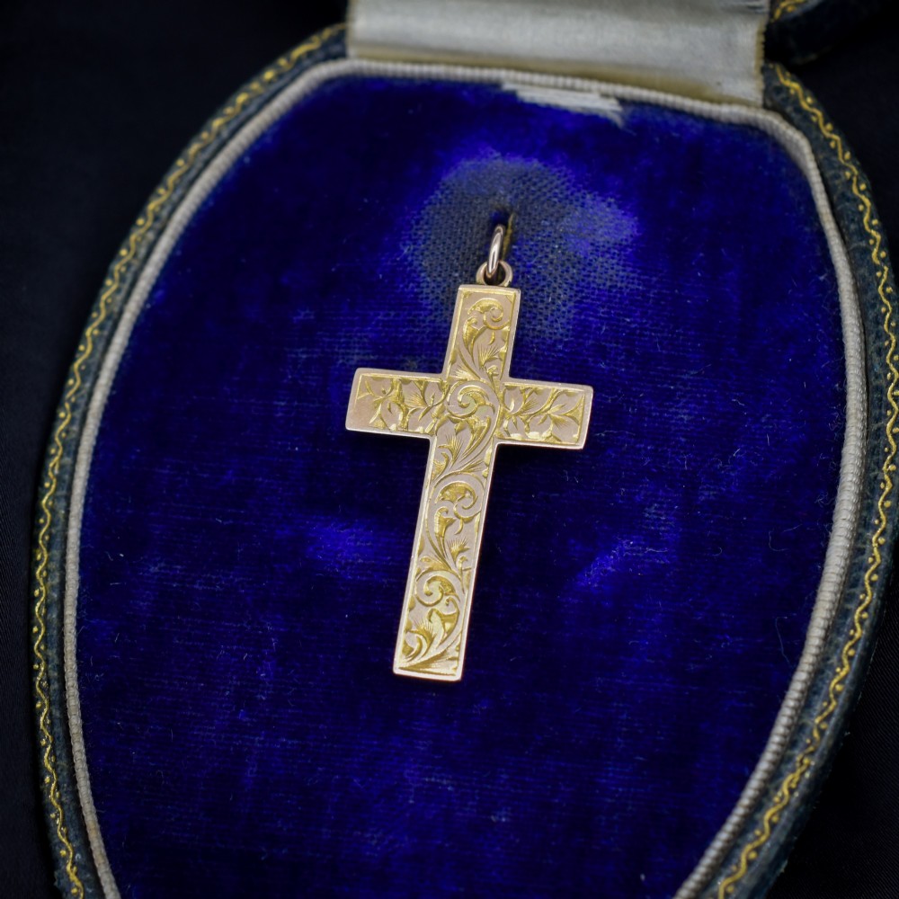 An Edwardian 9ct yellow gold cross pendant featuring hand-engraved ivy leaves and scrollwork patterns with a top suspension loop.