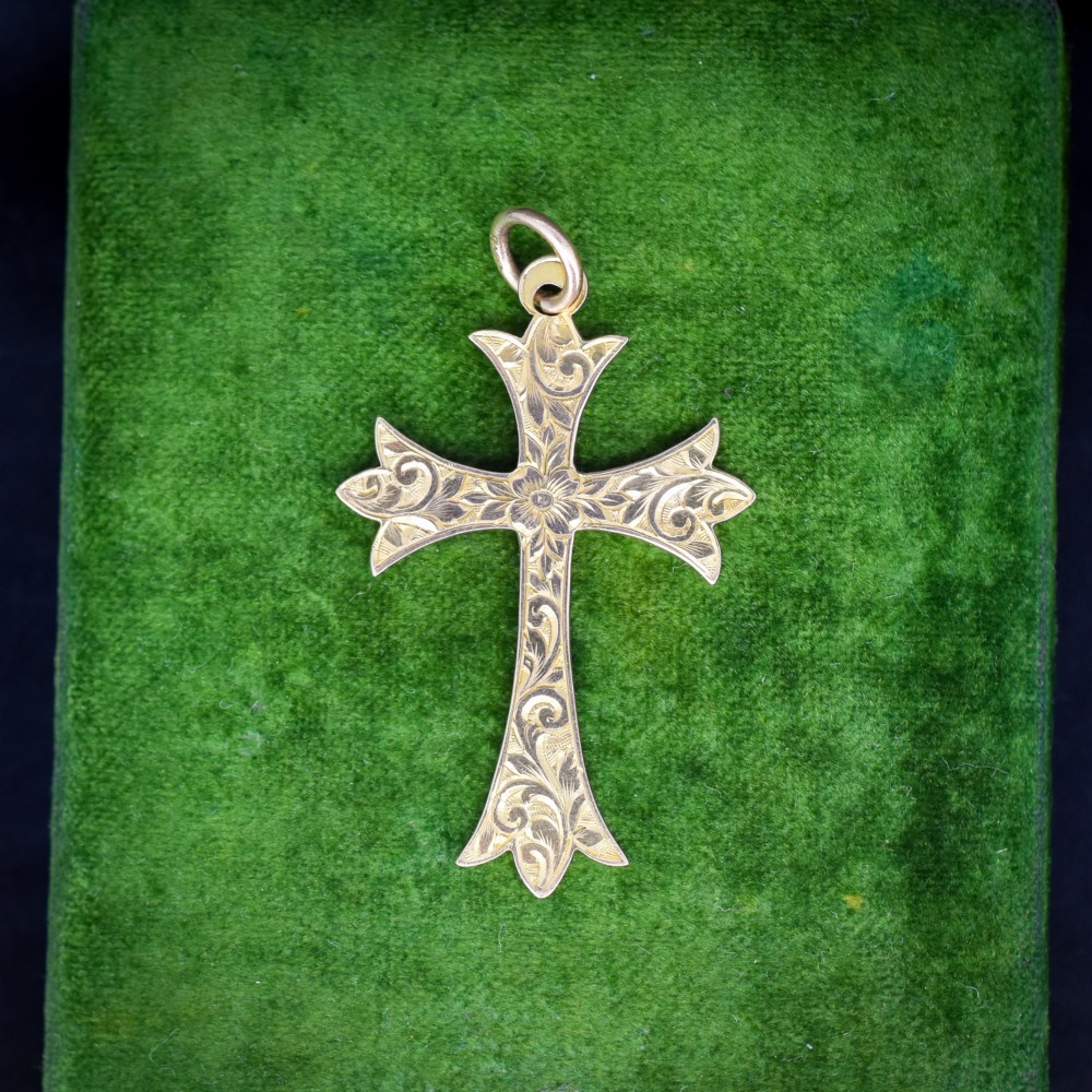An Edwardian 9ct yellow gold cross pendant with intricate foliate hand engraving and a top suspension ring.
