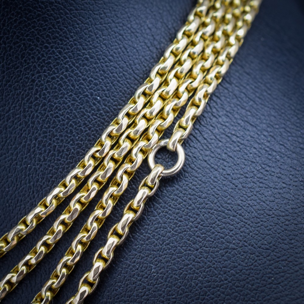 An antique 10ct yellow gold long guard chain featuring faceted oval links and a dog clip fastener. View V