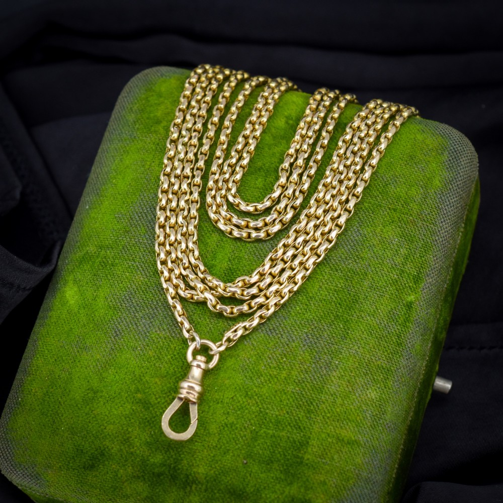 An antique 10ct yellow gold long guard chain featuring faceted oval links and a dog clip fastener.