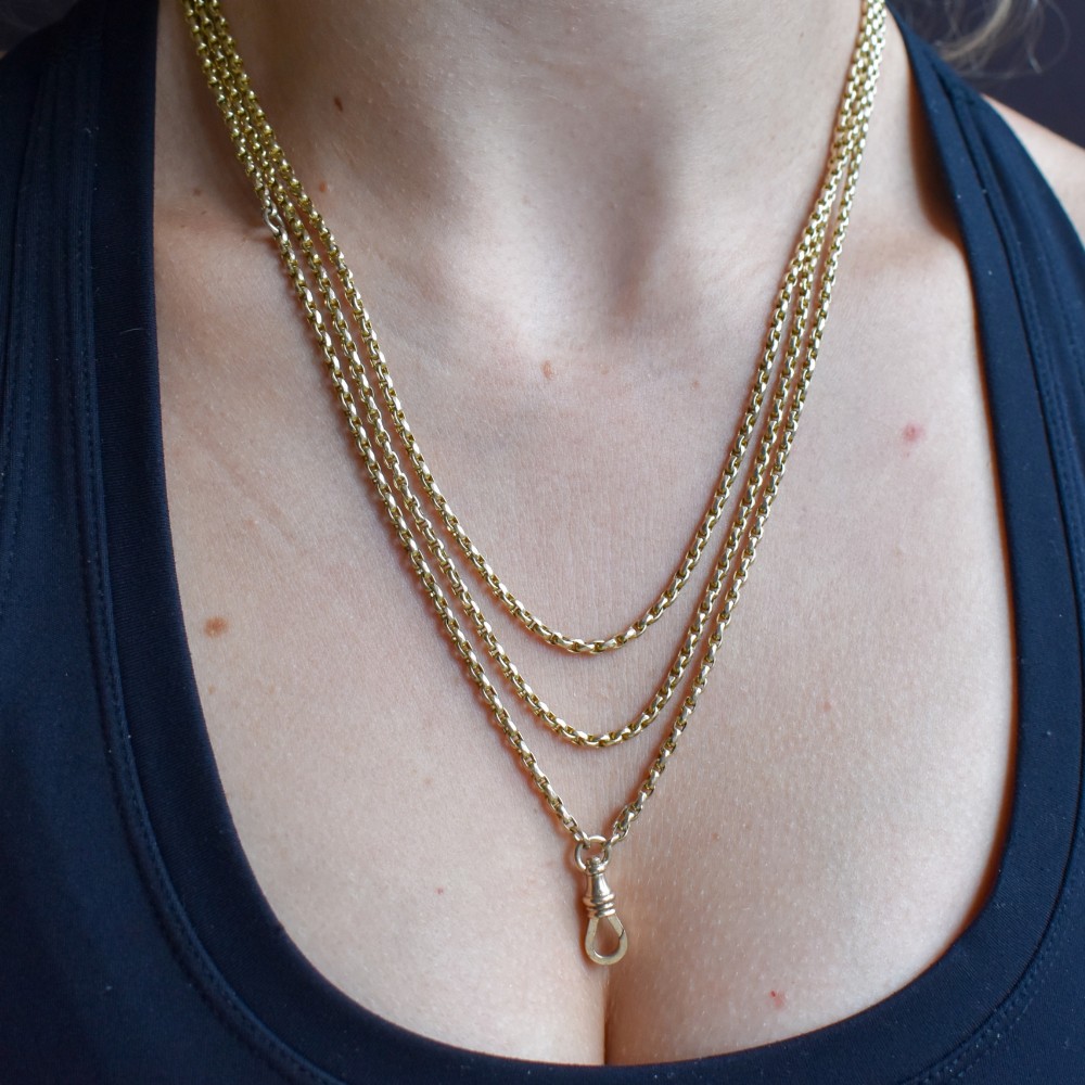 An antique 10ct yellow gold long guard chain featuring faceted oval links and a dog clip fastener. View X